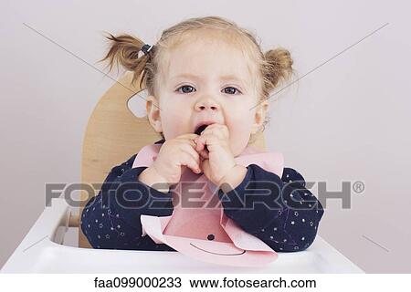 Baby girl sitting in high chair, eating snack View Large Photo Image Stock Image - Baby girl sitting in high chair, eating snack. Fotosearch