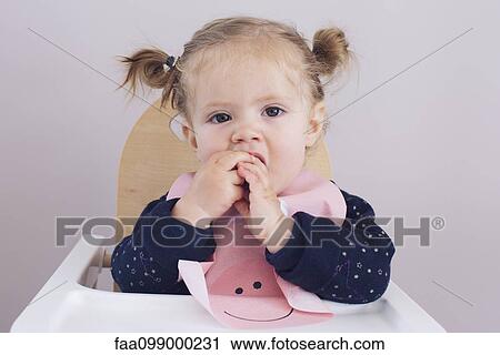Baby girl sitting in high chair, chewing on fingers View Large Photo Image Stock Image - Baby girl sitting in high chair, chewing on fingers. Fotosearch