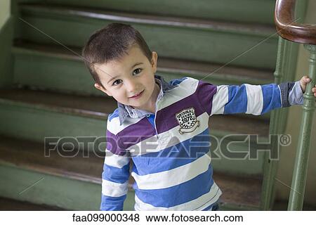 Boy standing at bottom of stairs, smiling, portrait View Large Photo Image Stock Photo - Boy standing at bottom of stairs, smiling, portrait. Fotosearch