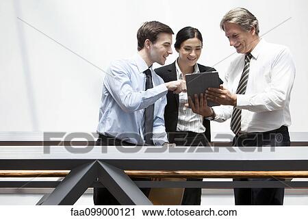 Stock Image - Business colleagues looking at digital tablet together. Fotosearch