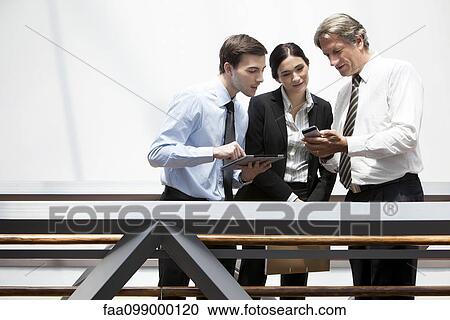 Stock Image - Business colleagues looking at smartphone together. Fotosearch