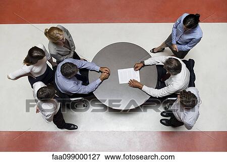 Businessmen flanked by support staff negotiate contract View Large Photo Image Stock Photo - Businessmen flanked by support staff negotiate contract. Fotosearch