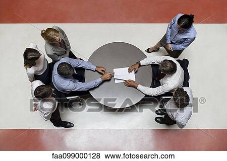 Businessmen flanked by support staff negotiate contract View Large Photo Image Stock Photo - Businessmen flanked by support staff negotiate contract. Fotosearch