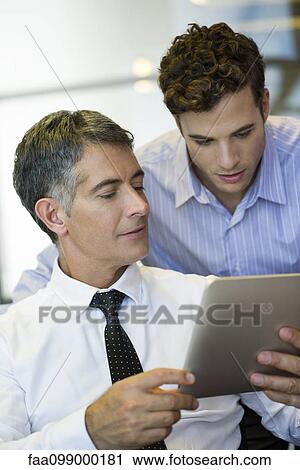 Stock Image - Businessmen showing assistant digital tablet. Fotosearch