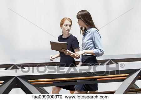 Businesswomen walking and talking together in corridor View Large Photo Image Stock Image - Businesswomen walking and talking together in corridor. Fotosearch