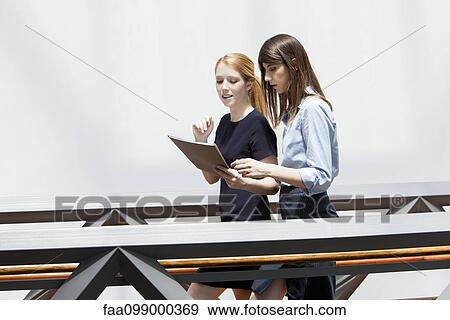 Stock Photo - Colleagues walking and discussing file together. Fotosearch