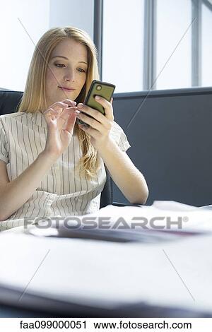 Stock Image - College student using smartphone during study break. Fotosearch