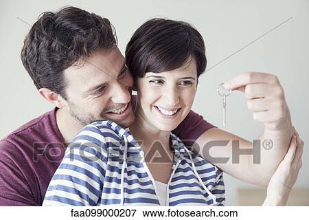 Stock Photo - Couple looking cheerfully at house key together. Fotosearch