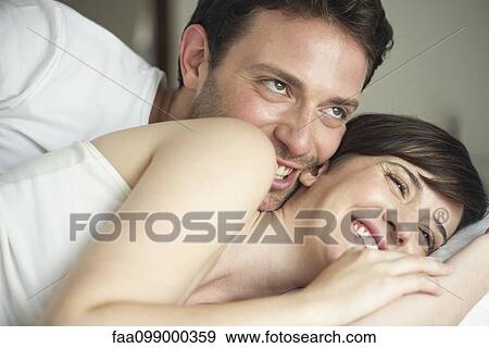 Couple playfully cuddling in bed View Large Photo Image Stock Photo - Couple playfully cuddling in bed. Fotosearch