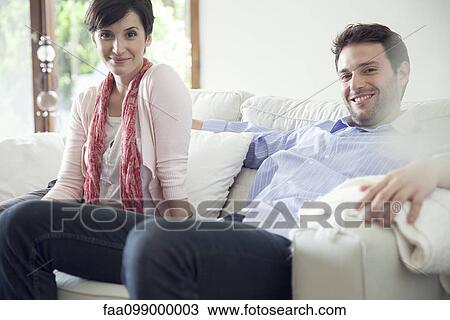 Stock Image - Couple relaxing on sofa at home. Fotosearch