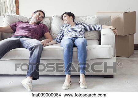 Picture - Couple relaxing on sofa while moving house. Fotosearch