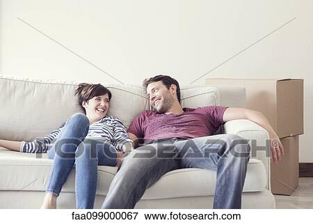 Stock Photo - Couple relaxing on sofa while moving house. Fotosearch