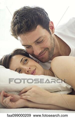 Stock Photo - Couple together in bed, wife giving husband knowing look. Fotosearch