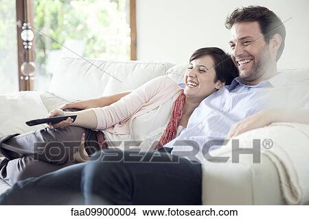 Picture - Couple watching TV together on sofa. Fotosearch