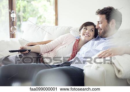 Stock Image - Couple watching TV together on sofa. Fotosearch