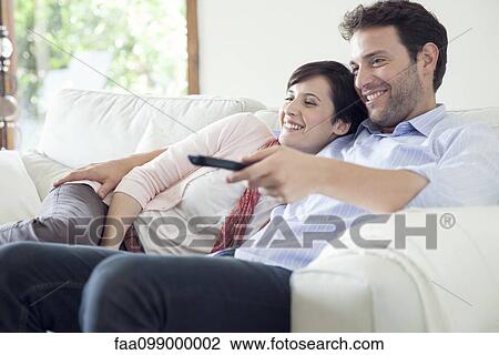 Stock Image - Couple watching TV together on sofa. Fotosearch