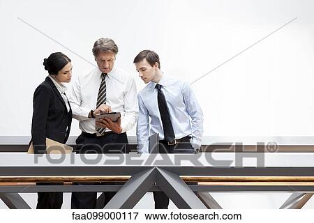 Executives looking at digital tablet together View Large Photo Image Stock Photo - Executives looking at digital tablet together. Fotosearch