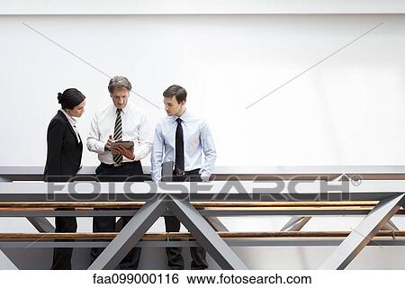 Stock Photograph - Executives looking at digital tablet together. Fotosearch