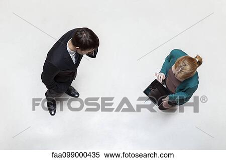 Stock Photography - Executives standing in lobby, woman using digital tablet, overhead view. Fotosearch