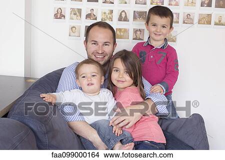 Picture - Father and children sitting together on sofa, portrait. Fotosearch