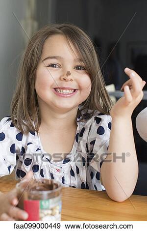 Stock Photo - Little girl eating chocolate sauce from a jar with her fingers. Fotosearch