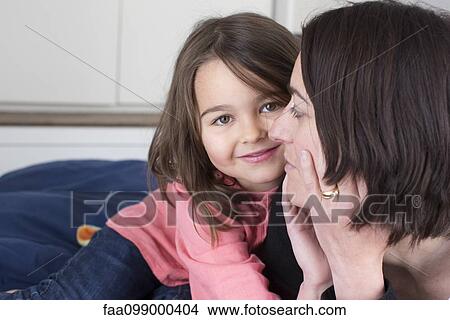 Picture - Little girl embracing her mother and smiling. Fotosearch