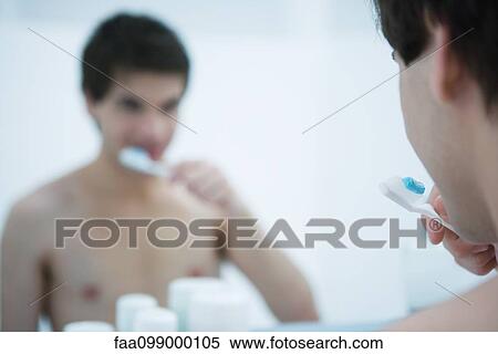 Stock Photography - Man looking in mirror, brushing teeth, cropped. Fotosearch