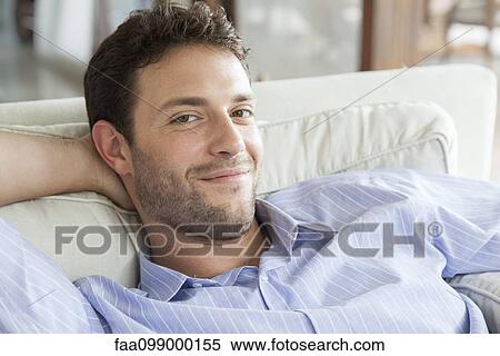 Man relaxing on sofa, portrait View Large Photo Image Stock Photography - Man relaxing on sofa, portrait. Fotosearch