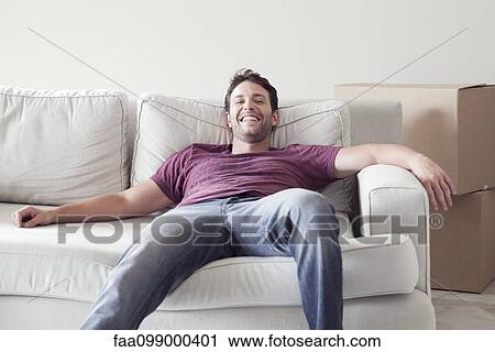 Man relaxing on sofa while moving house View Large Photo Image Stock Image - Man relaxing on sofa while moving house. Fotosearch