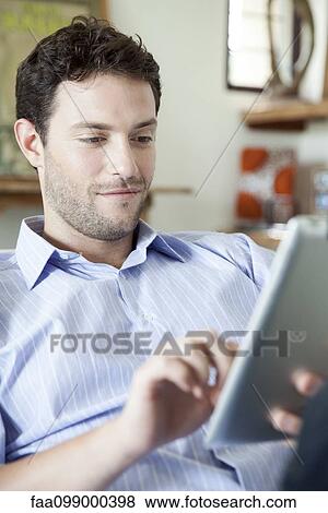 Man using digital tablet at home View Large Photo Image Stock Photo - Man using digital tablet at home. Fotosearch