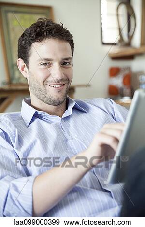 Stock Photo - Man using digital tablet, smiling at camera. Fotosearch