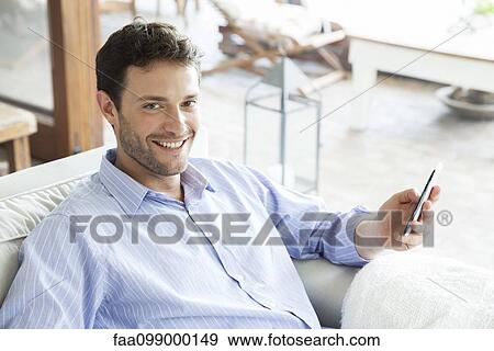 Man using smartphone, smiling View Large Photo Image Stock Photo - Man using smartphone, smiling. Fotosearch