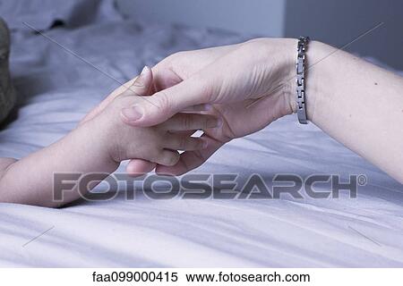Stock Photography - Mother's hand holding baby's hand, close-up. Fotosearch
