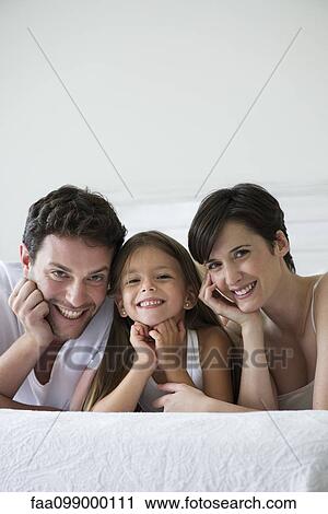 Parents and daughter lying on bed together, portrait View Large Photo Image Stock Image - Parents and daughter lying on bed together, portrait. Fotosearch