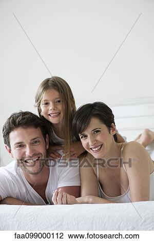 Parents and daughter lying on bed together, portrait View Large Photo Image Stock Image - Parents and daughter lying on bed together, portrait. Fotosearch