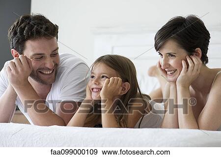 Parents and daughter lying on bed together, portrait View Large Photo Image Stock Photo - Parents and daughter lying on bed together, portrait. Fotosearch