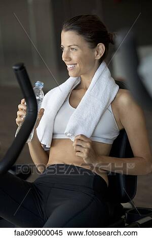 Woman drinking bottled water in health club View Large Photo Image Stock Photography - Woman drinking bottled water in health club. Fotosearch