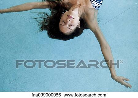 Stock Photograph - Woman floating in pool with eyes closed. Fotosearch