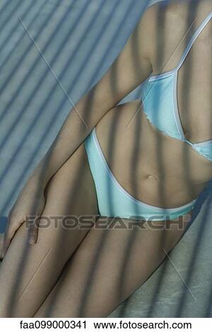 Stock Image - Woman in bikini sitting in shade, cropped. Fotosearch
