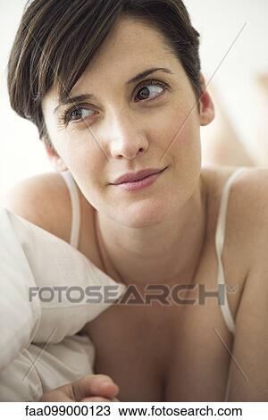 Stock Image - Woman lying on bed contemplating her private future. Fotosearch