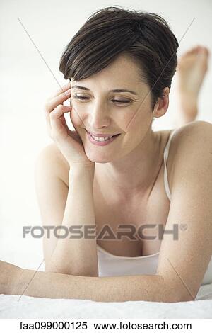 Woman lying on bed with look of contentment, portrait View Large Photo Image Stock Photography - Woman lying on bed with look of contentment, portrait. Fotosearch