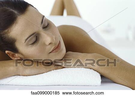 Stock Photography - Woman lying on stomach with head resting on arms, eyes closed. Fotosearch