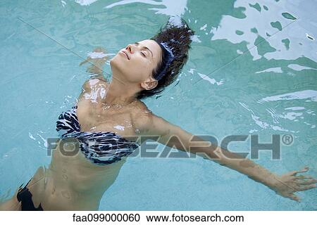 Stock Image - Woman relaxing in pool with eyes closed. Fotosearch