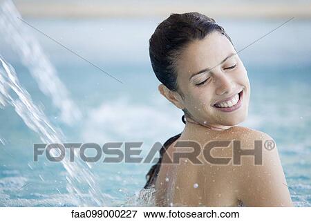 Woman relaxing under fountain in pool View Large Photo Image Stock Photo - Woman relaxing under fountain in pool. Fotosearch