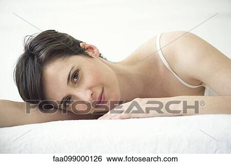 Stock Photograph - Woman resting on bed, portrait. Fotosearch