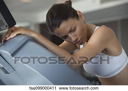Woman resting on exercise machine in health club View Large Photo Image Stock Image - Woman resting on exercise machine in health club. Fotosearch