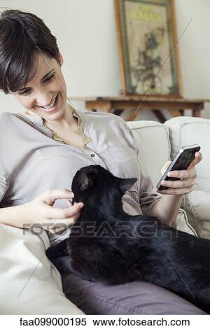 Woman sitting on sofa with cat on her lap View Large Photo Image Stock Photography - Woman sitting on sofa with cat on her lap. Fotosearch