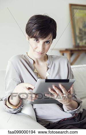 Picture - Woman using digital tablet at home. Fotosearch