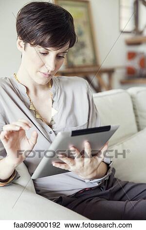 Stock Image - Woman using digital tablet at home. Fotosearch
