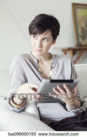 Woman using digital tablet at home View Large Photo Image Stock Image - Woman using digital tablet at home. Fotosearch